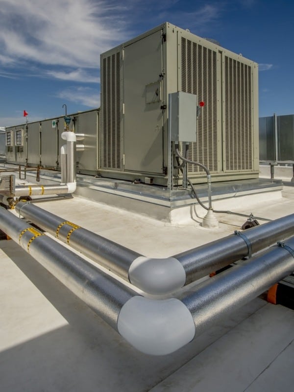 commercial HVAC unit on roof surrounded in pipes